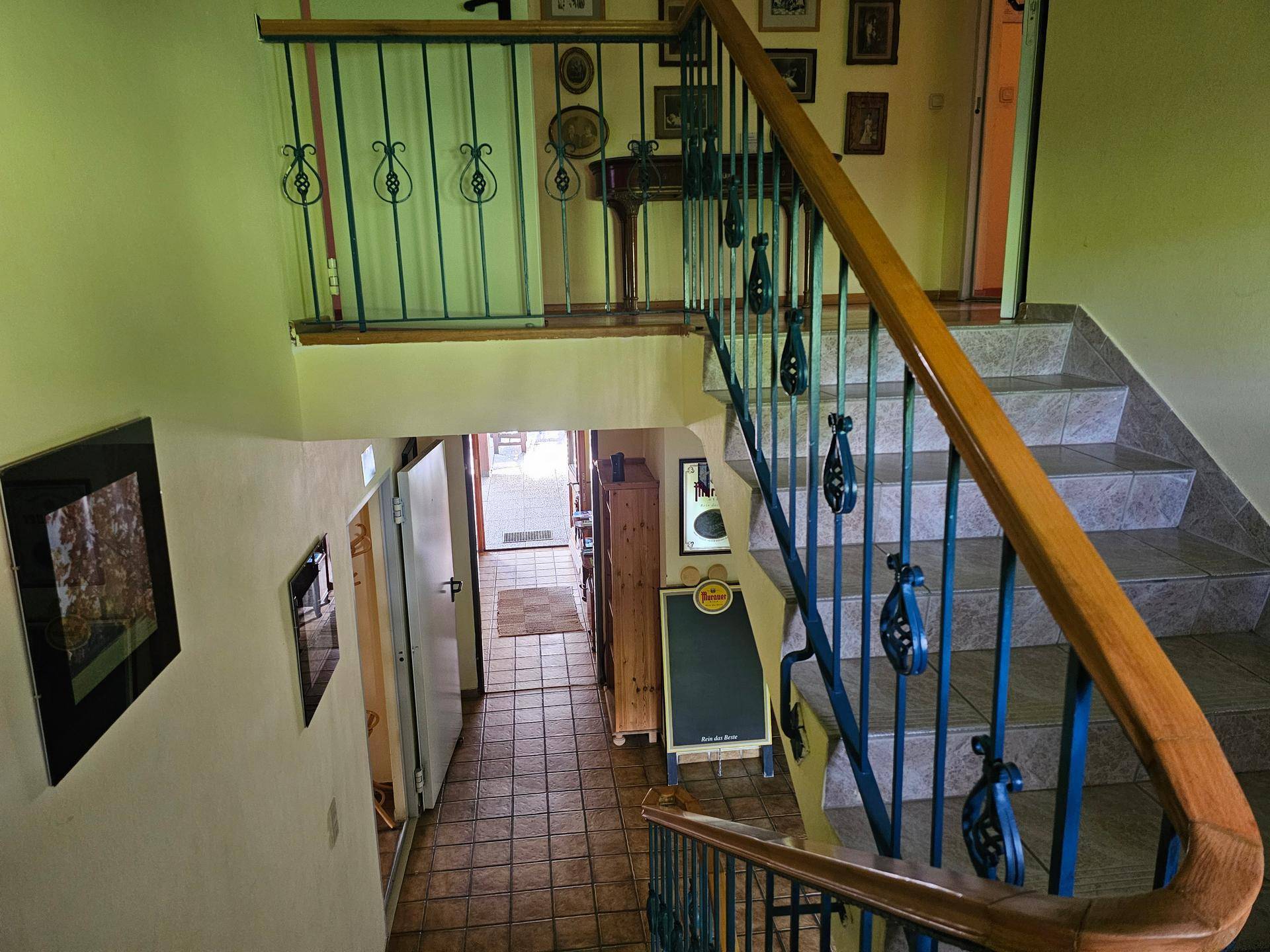 Treppenhaus mit gefliesten Stufen und einem verzierten Metallgeländer, das in die untere Etage führt.