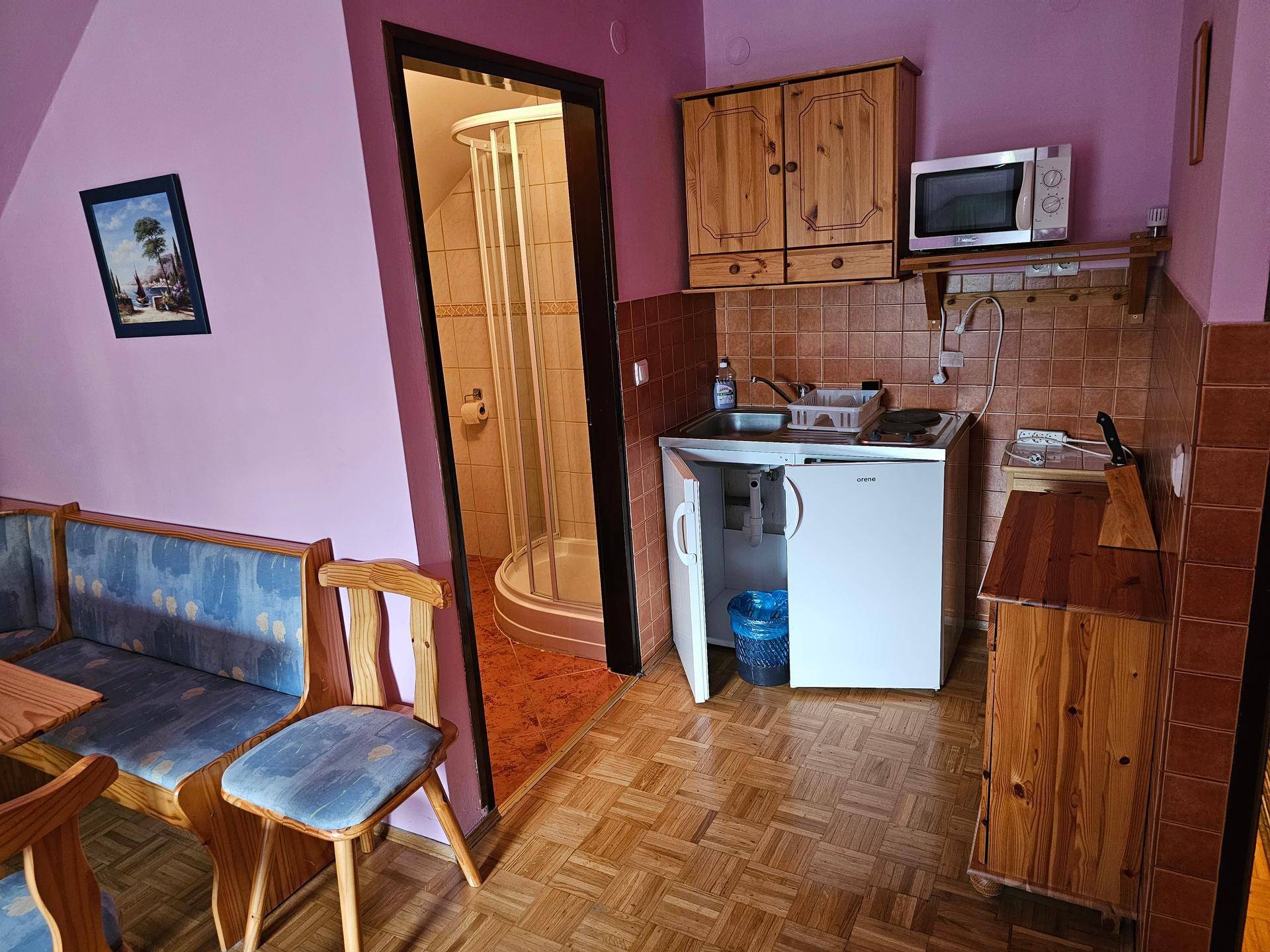 Kleine Küchenzeile mit Spüle, Mikrowelle und Kühlschrank, angrenzend an einen Essbereich.