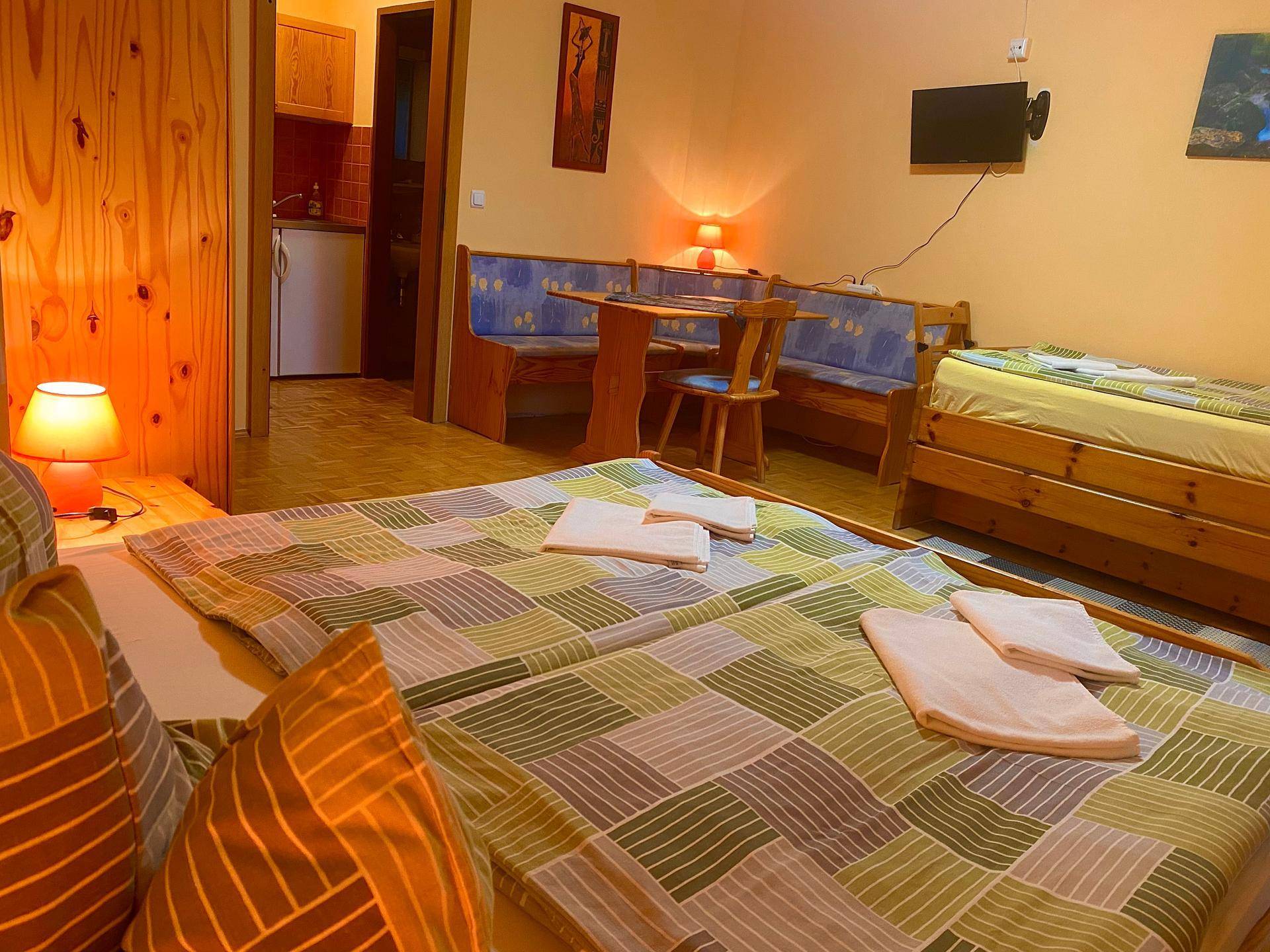 Studio-Apartment mit Doppelbett, Essbereich mit Eckbank und einer Küchenzeile im Hintergrund.