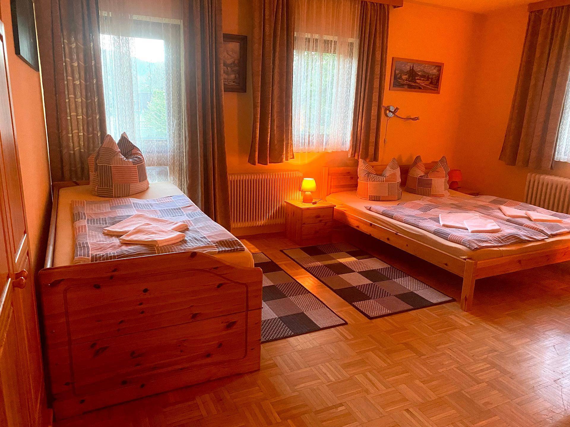 Schlafzimmer mit zwei Einzelbetten, einem kleinen Tisch und einem Fenster mit Blick nach draußen.