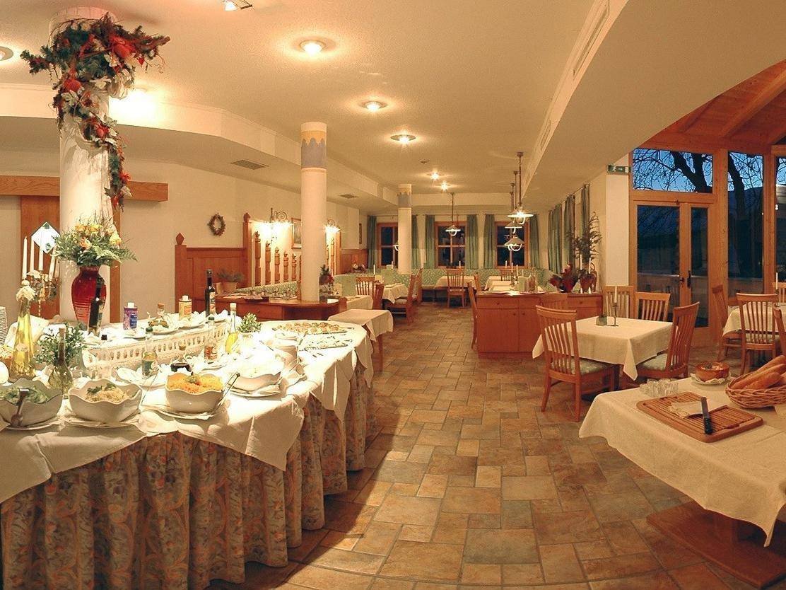 Geräumiger Speisesaal mit Buffet, gefliestem Boden und Holztischen, der eine gemütliche Atmosphäre bietet.