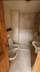 Helles Badezimmer mit Dusche, WC und Bidet, komplett gefliest in neutralen Farben.
