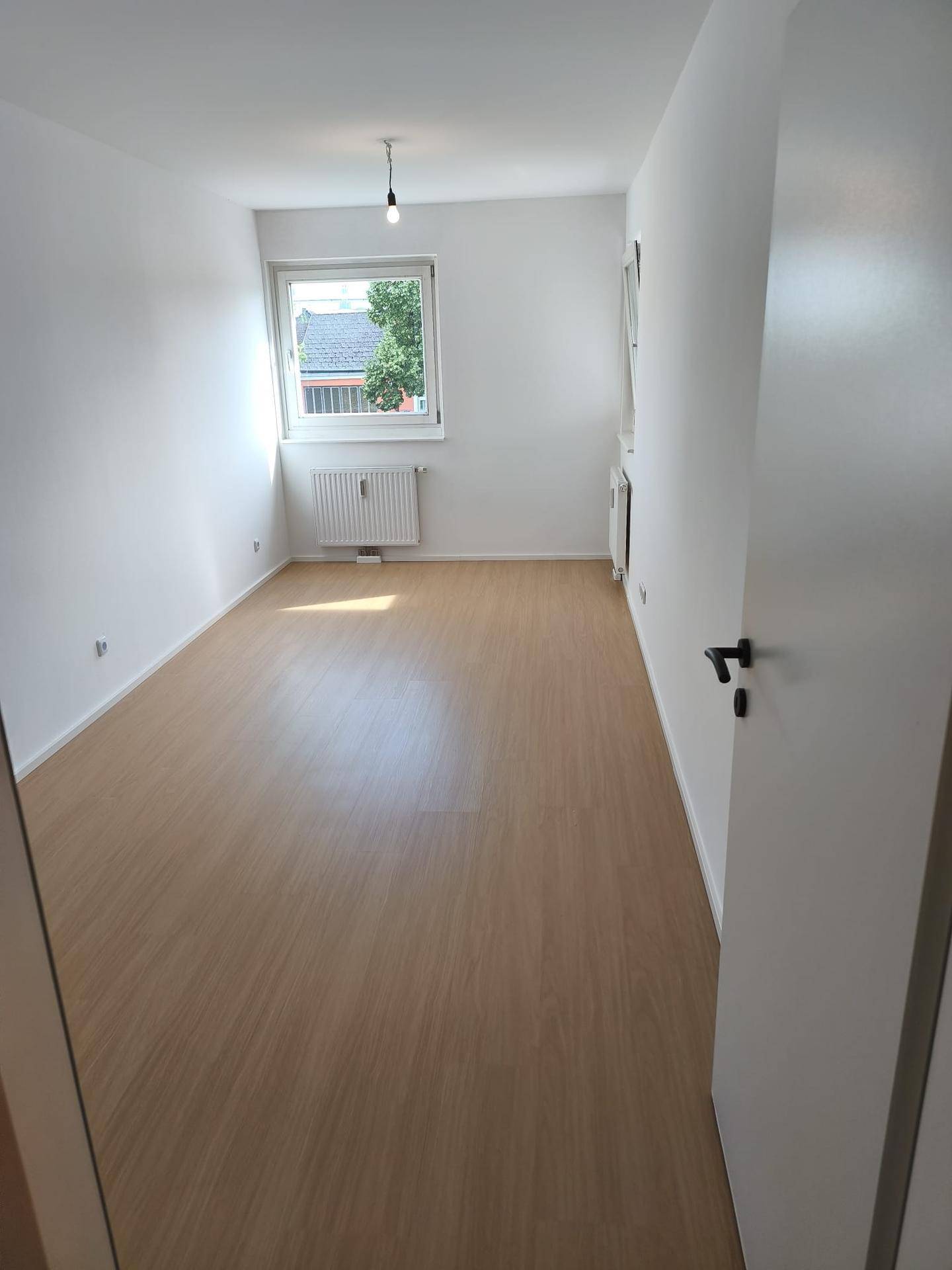 Helles Zimmer mit Laminatboden und Fenster, ideal als Schlaf- oder Arbeitszimmer.