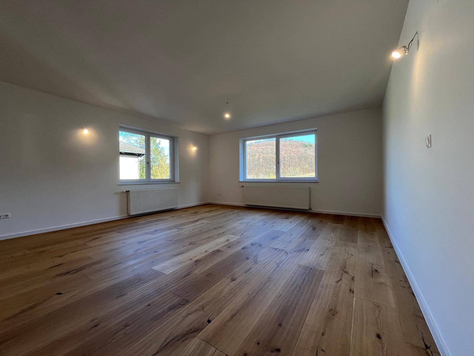 Helles Zimmer mit Holzparkett und zwei Fenstern für optimale Belichtung.