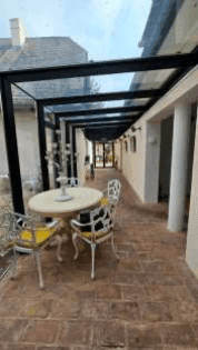 Überdachte Terrasse mit Ziegelboden und schmiedeeisernen Möbeln, ideal für entspannte Stunden.