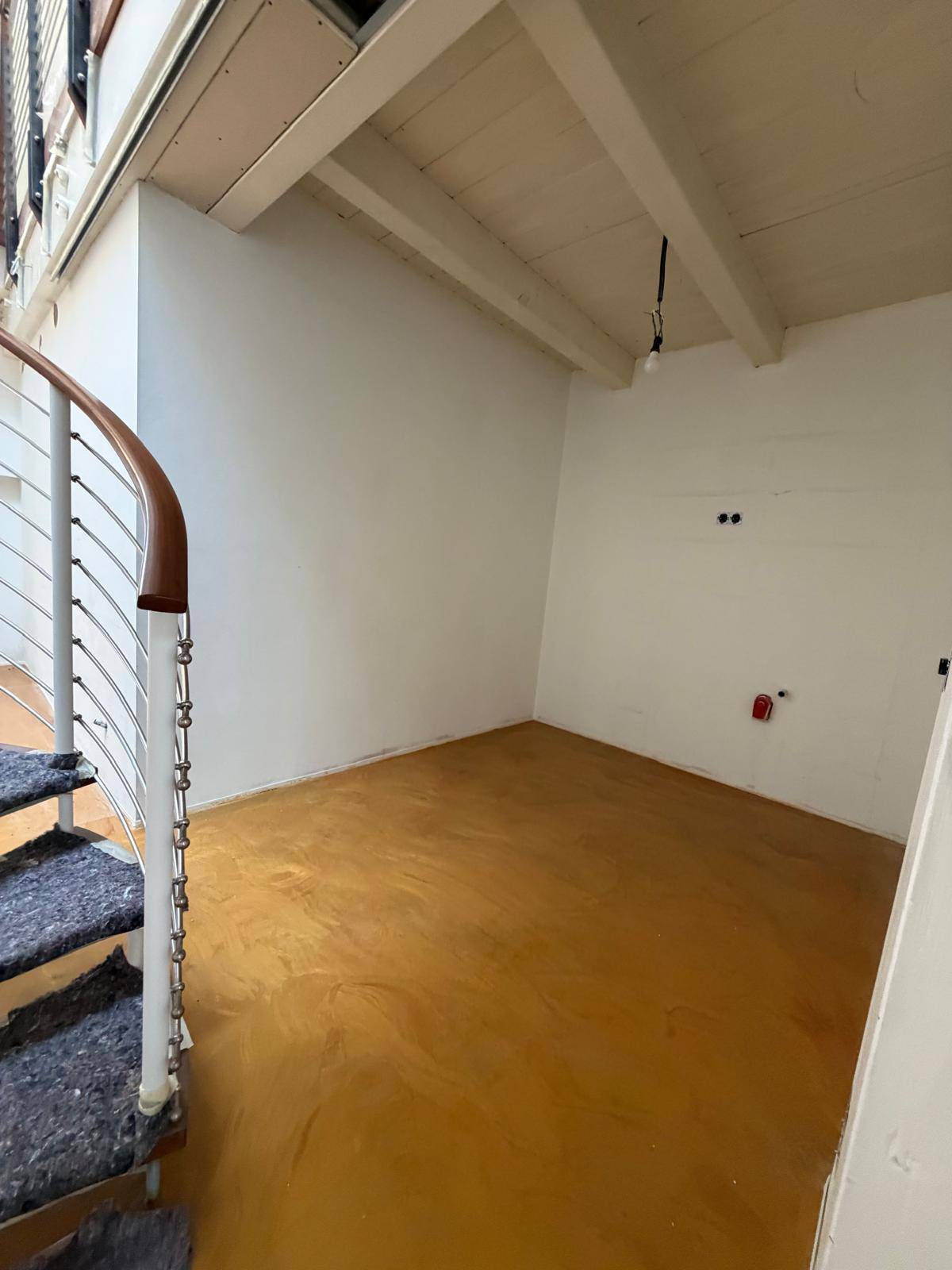 Raum im Bau mit gelbem Boden, weißen Wänden und einem Teil der Wendeltreppe.