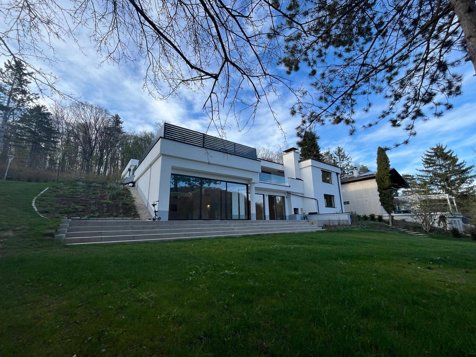 Weitläufige Ansicht der modernen Villa mit großem Garten und Blick auf die umliegende Natur.