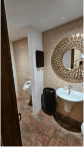 Gäste-WC mit Urinal, Einzelwaschbecken und dekorativem Spiegel, komplett gefliest.