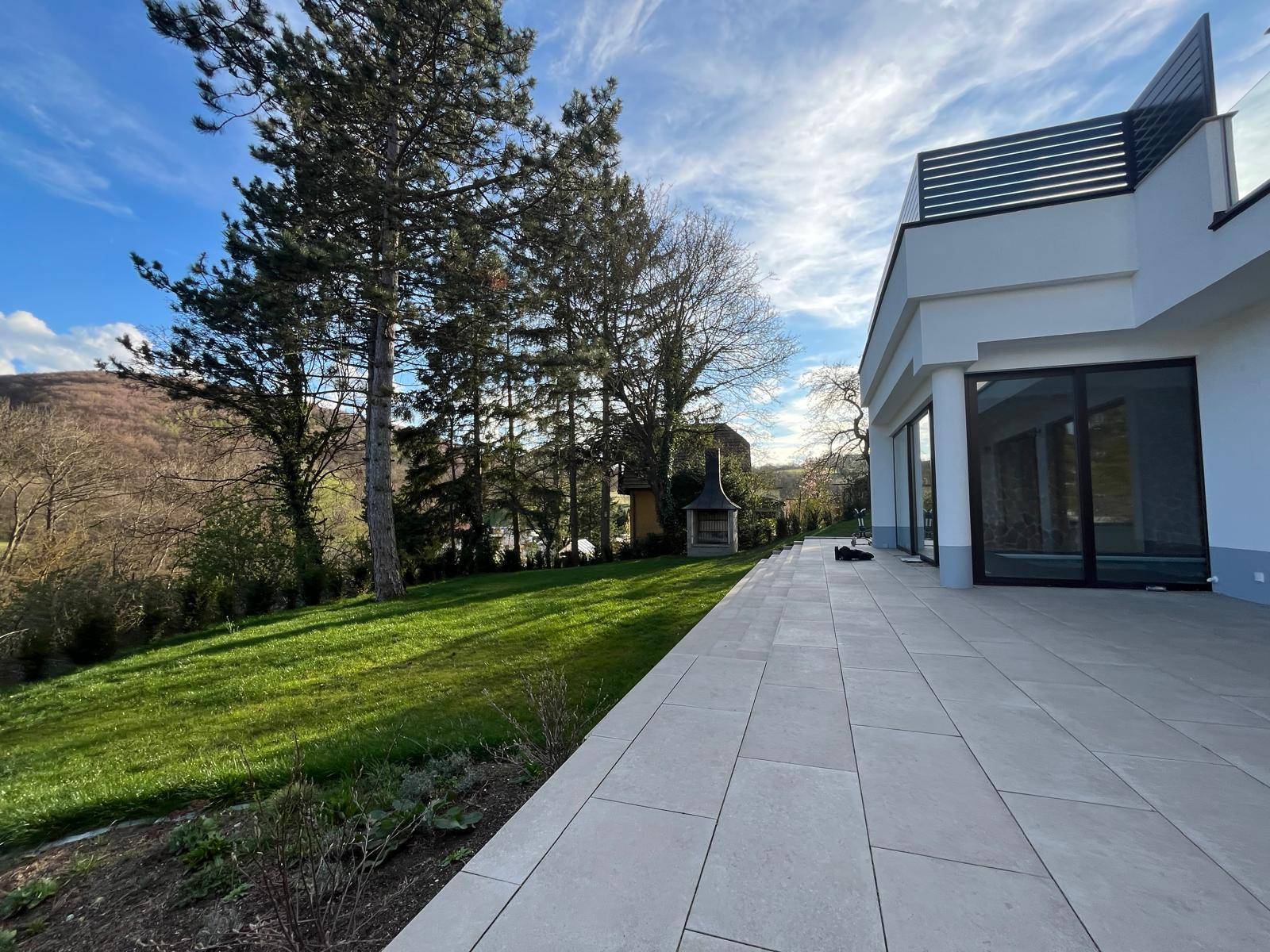 Geräumige Terrasse mit Fliesenboden und angrenzendem Rasenbereich, ideal für Entspannung im Freien.