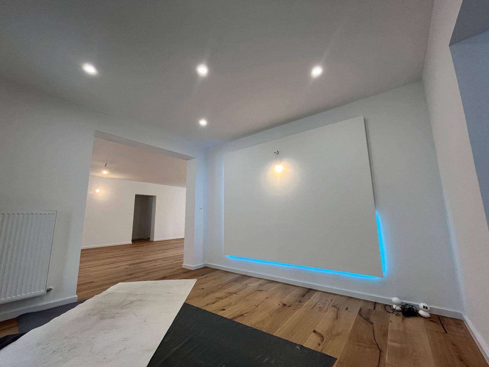 Moderner Wohnbereich mit Holzparkett und indirekter blauer Beleuchtung an der Wand.
