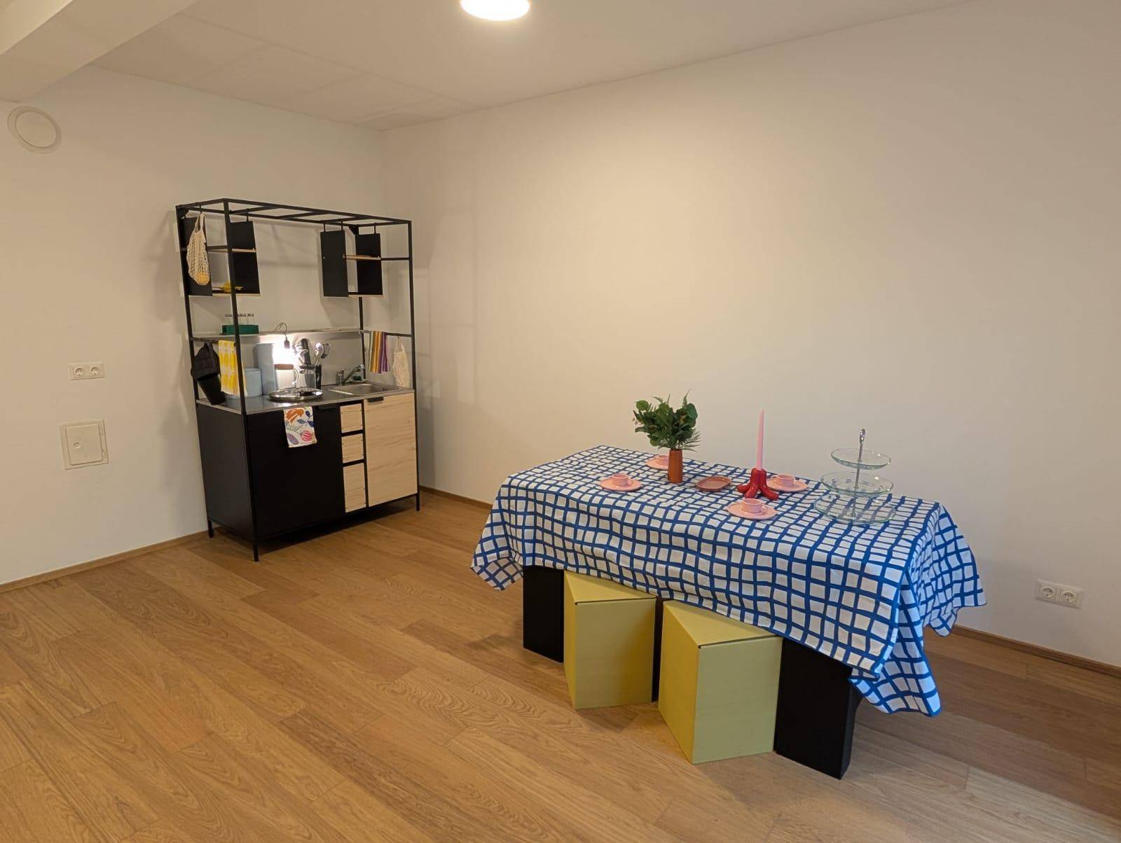 Offener Wohnbereich mit kleiner Küchenzeile, Esstisch und modernem Holzboden.
