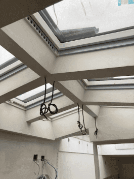 Decke eines im Bau befindlichen Raumes mit mehreren großen Dachfenstern für viel Tageslicht.