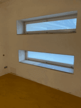 Zwei schmale Fenster in einem im Bau befindlichen Raum, die Tageslicht spenden.
