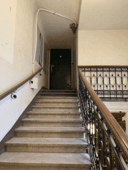 Historisches Treppenhaus in einem Altbau mit Marmorstufen und schmiedeeisernem Geländer.