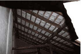 Nahaufnahme des Dachstuhls mit Holzbalken und Dachziegeln im ungenutzten Dachbodenbereich.