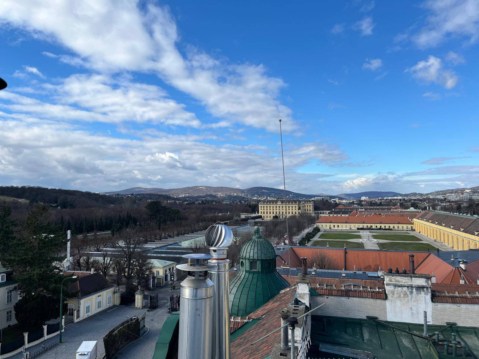 Spektakulärer Blick auf Schloss Schönbrunn und die umliegenden Gärten unter blauem Himmel.