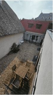Innenhof mit Holzterrasse und Kiesfläche, von oben betrachtet, umgeben von Gebäuden.