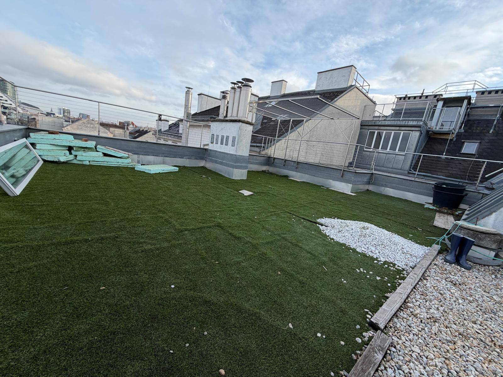 Große Dachterrasse mit Kunstrasen und Kiesflächen, bereit zur Gestaltung.