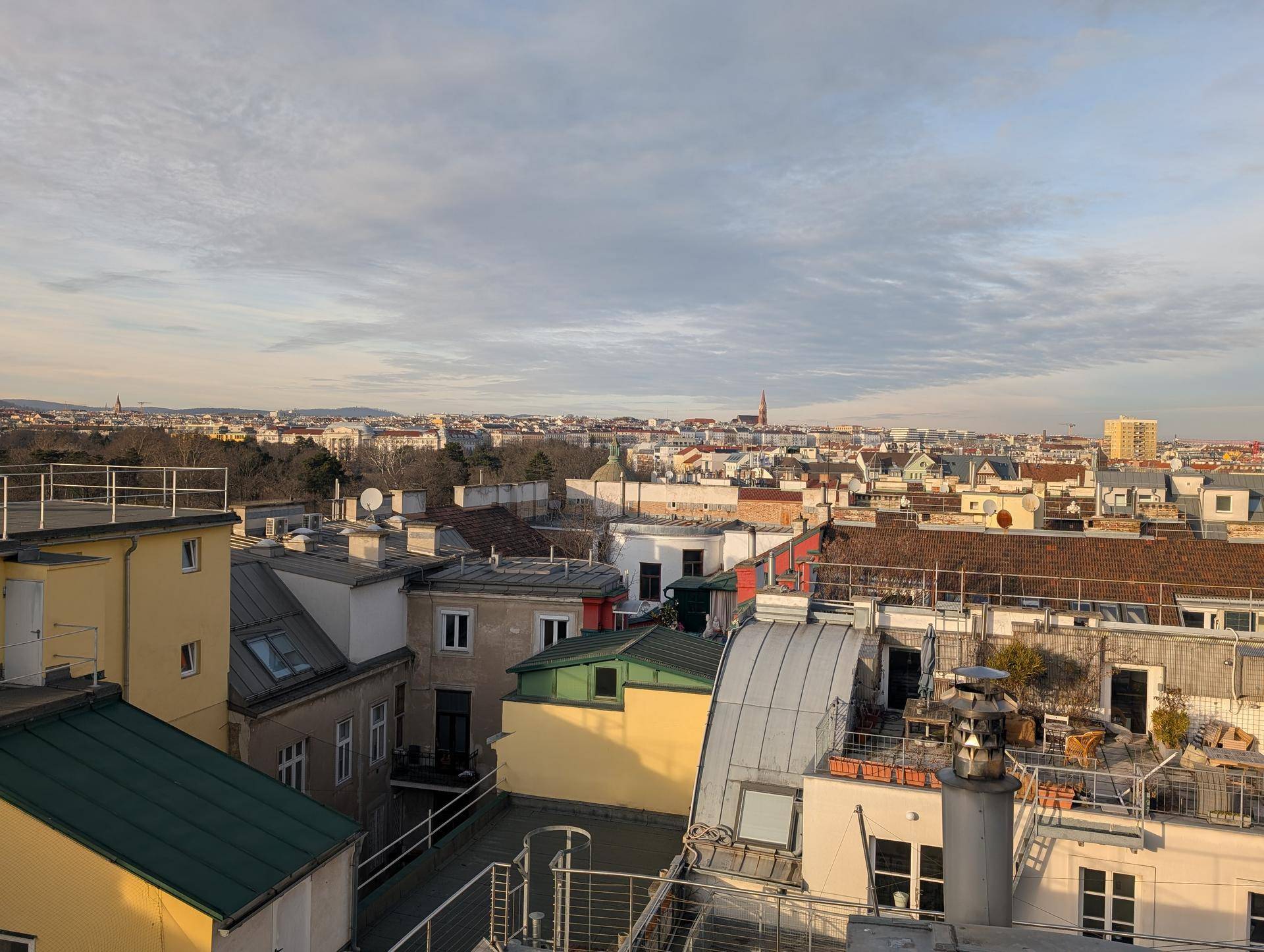 Weitläufiger Blick über die Dächer der Stadt mit verschiedenen Gebäuden und einem Hauch von Grün.