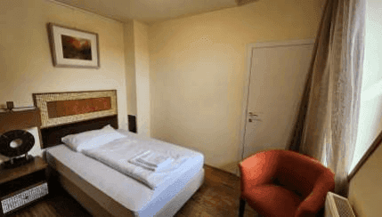 Gemütliches Schlafzimmer mit Einzelbett, Holzboden und Fenster, hell und funktional.