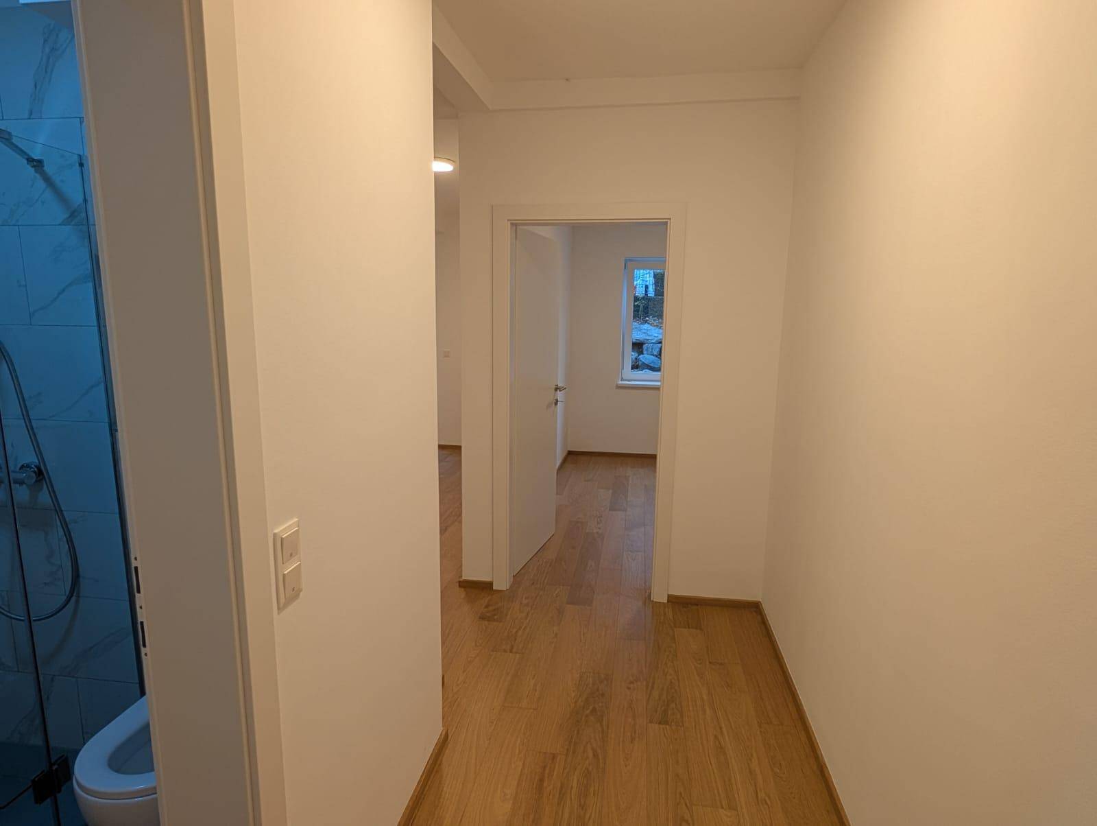 Heller Flur mit Holzboden, weißen Wänden und Zugang zu den angrenzenden Räumen.