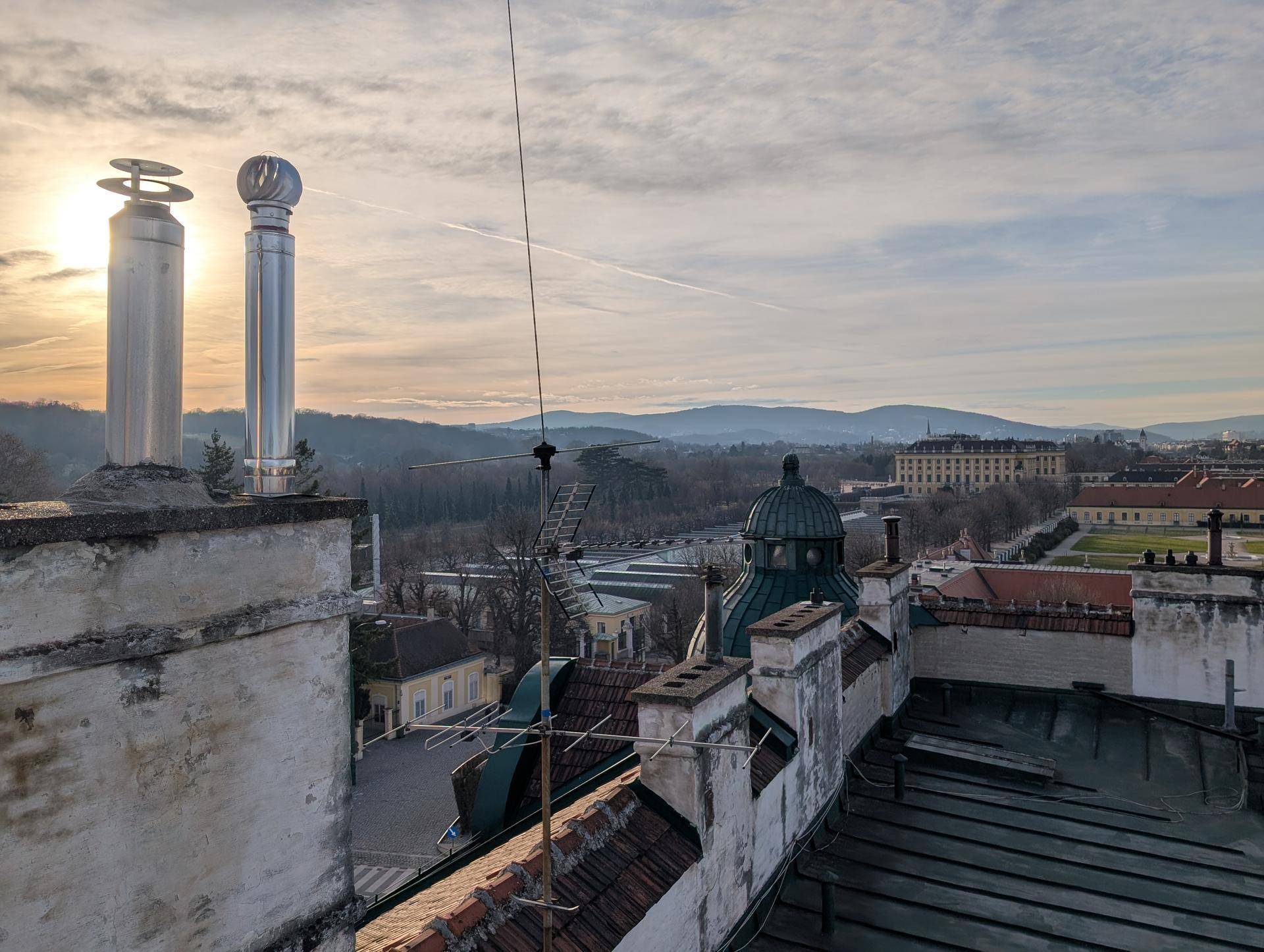 Sonnenaufgang über den Dächern mit Blick auf historische Gebäude und die umliegende Berglandschaft.