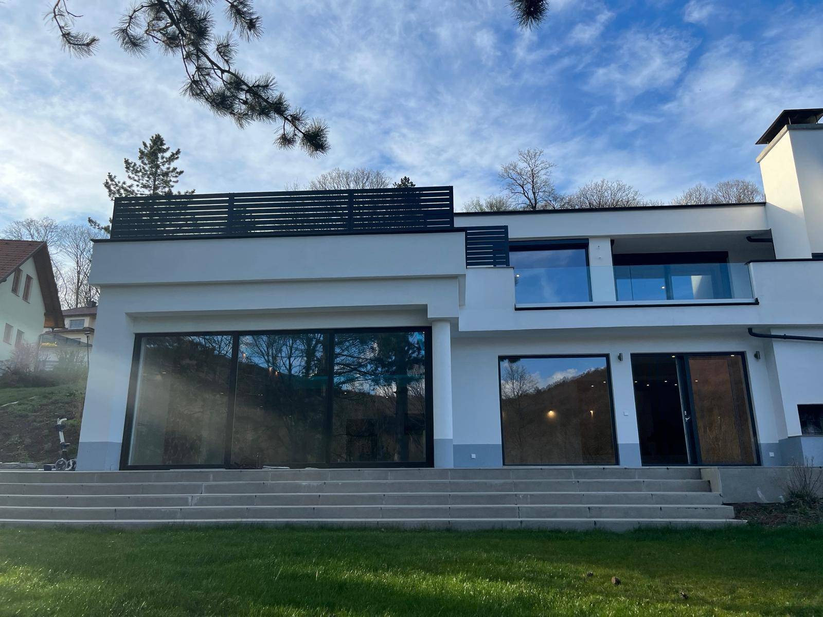 Ansicht der modernen Villa mit großen Fensterfronten und Zugang zum Gartenbereich.