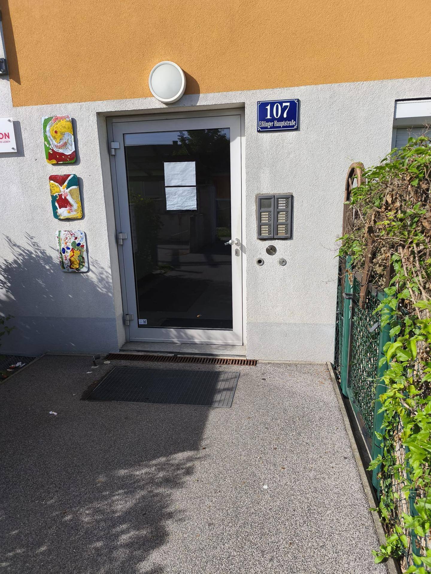 Nahaufnahme des Haupteingangs mit Hausnummer 107 und Gegensprechanlage.