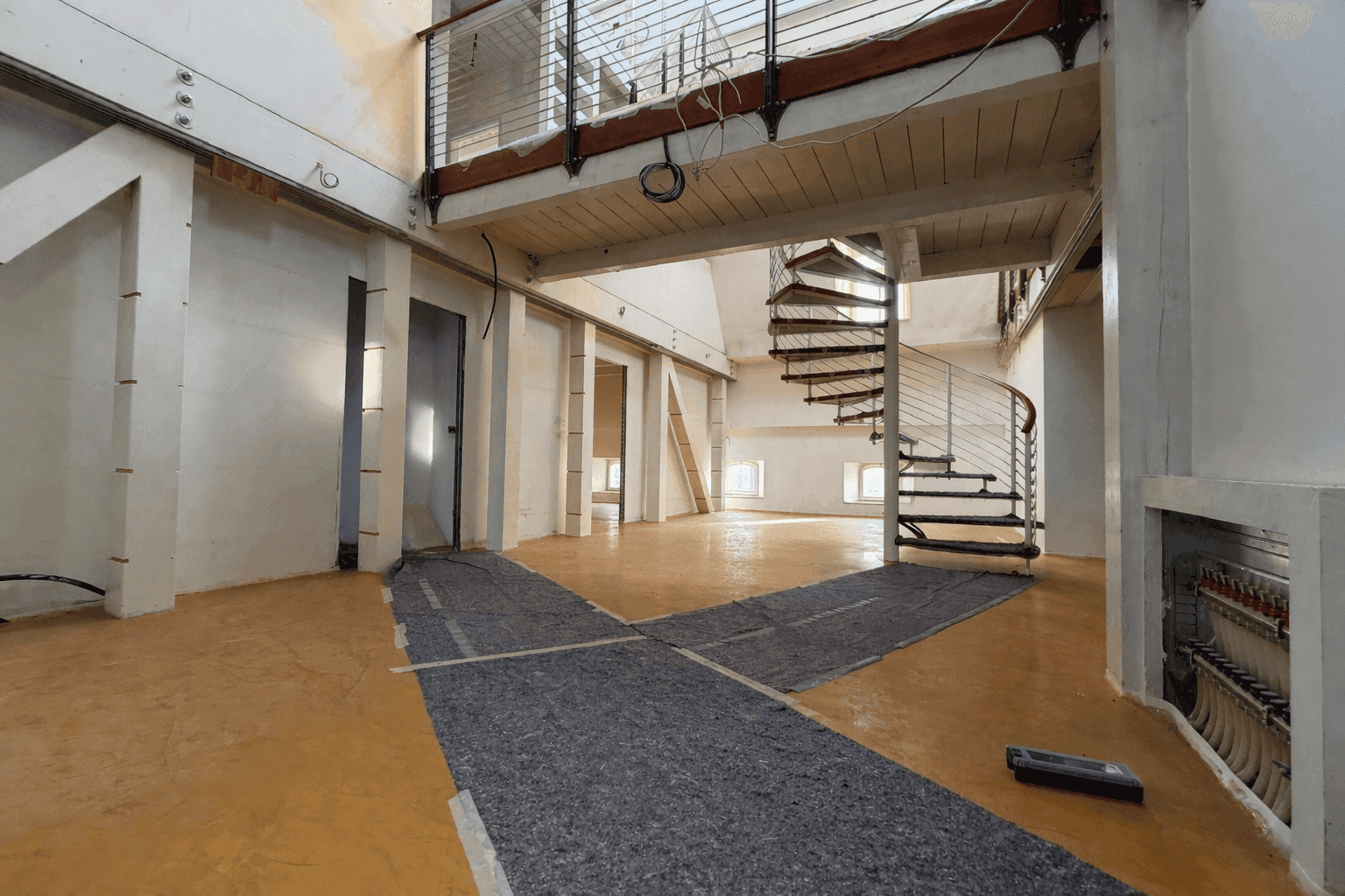 Unfertiger Innenraum mit Wendeltreppe und offener Galerie, bereit für den Ausbau.
