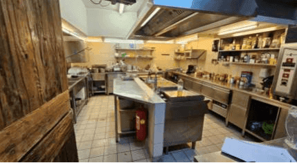 Professionelle Edelstahlküche mit umfangreicher Ausstattung und Abluftsystem für Gastronomie.