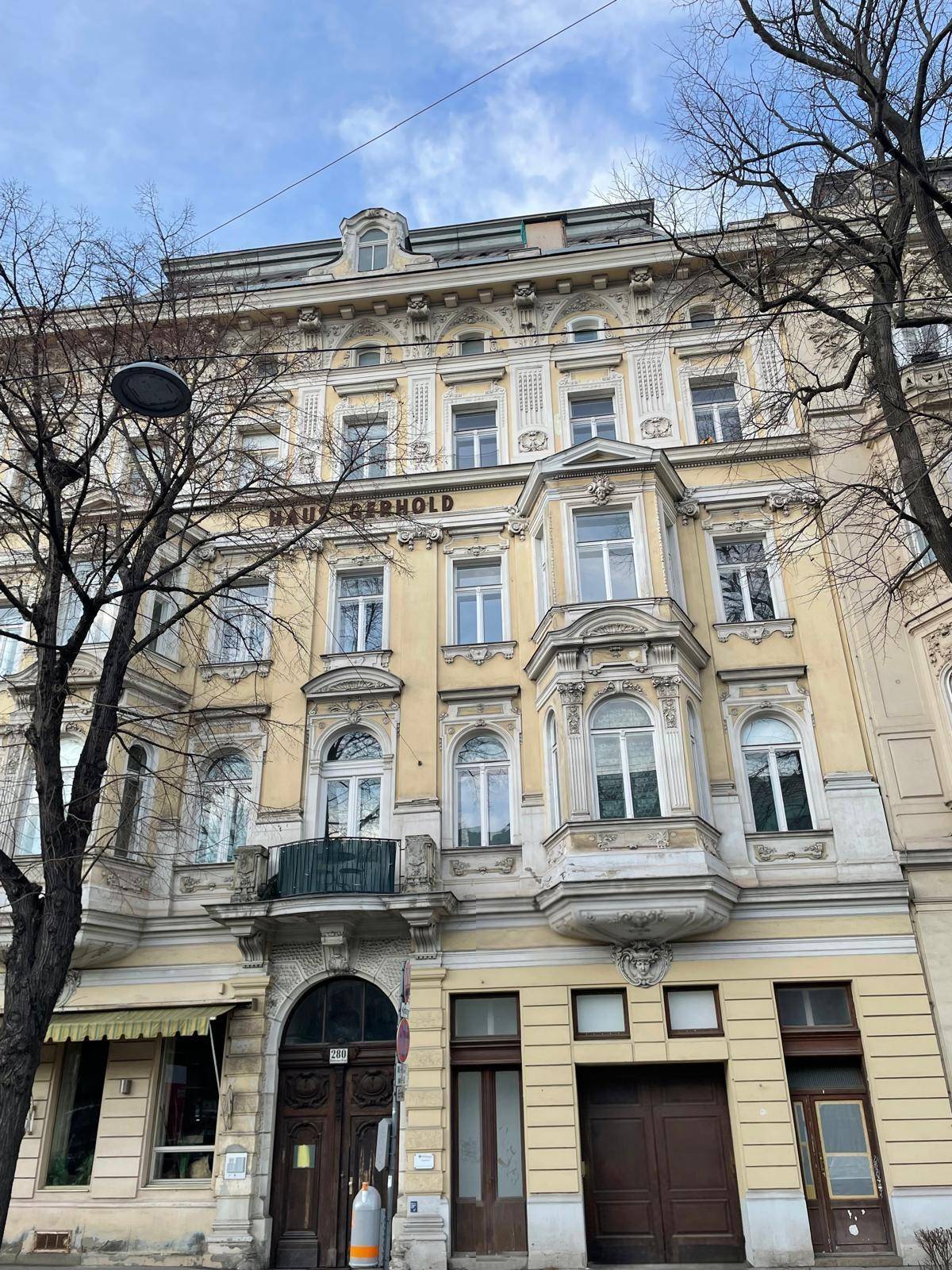 Historische Fassade eines Altbaus mit Stuckelementen und großen Fenstern.