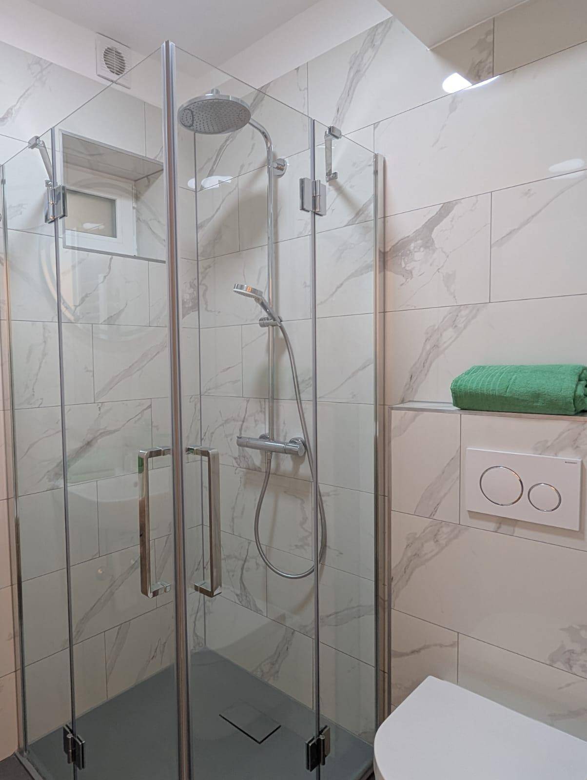 Elegantes Badezimmer mit großer Duschkabine, Marmoroptik-Fliesen und moderner Ausstattung.