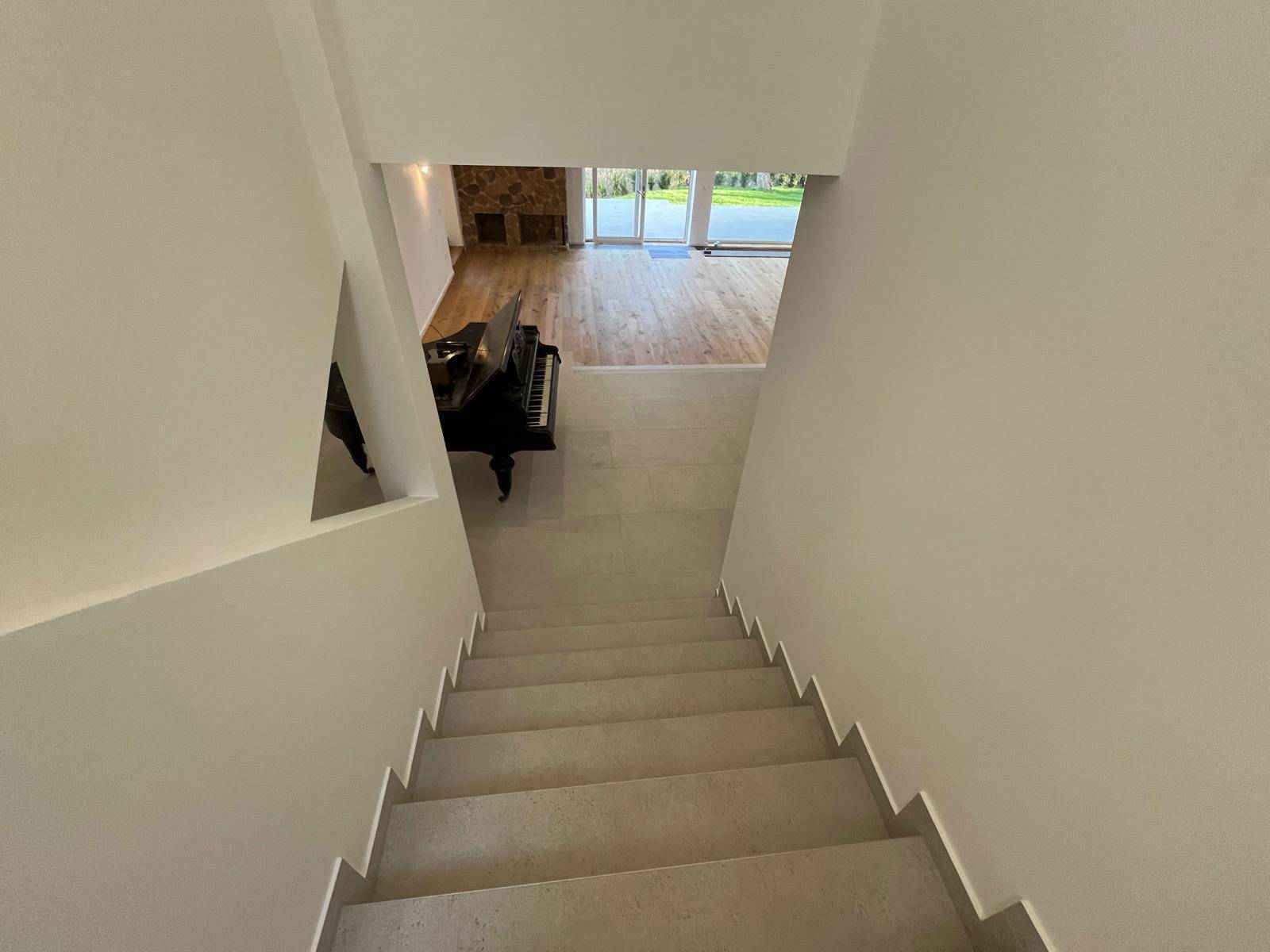 Elegante Treppe mit Fliesenstufen, die zu den unteren Wohnbereichen führt.