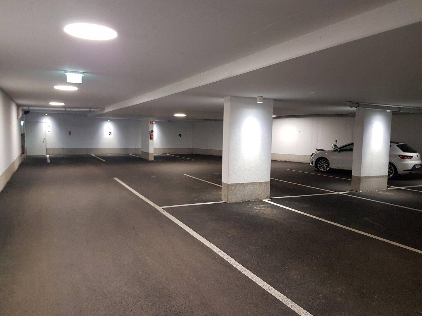 Helle und gepflegte Tiefgarage mit markierten Stellplätzen und moderner Beleuchtung.