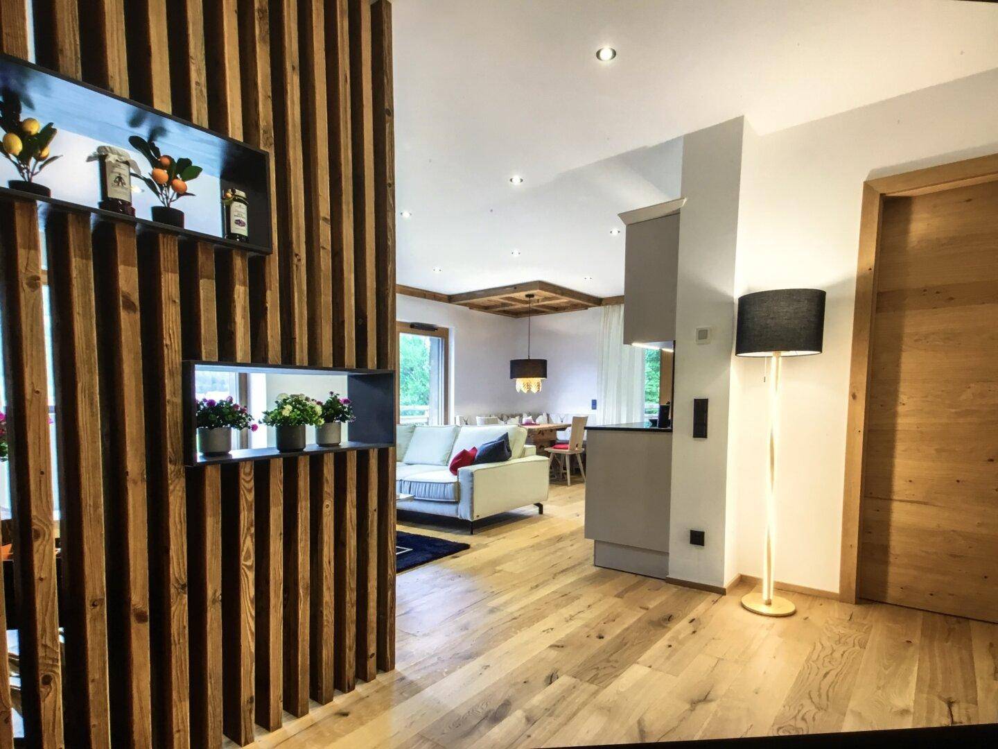 Einladender Eingangsbereich mit Holztrennwand, Garderobe und offenem Blick in den Wohnbereich.