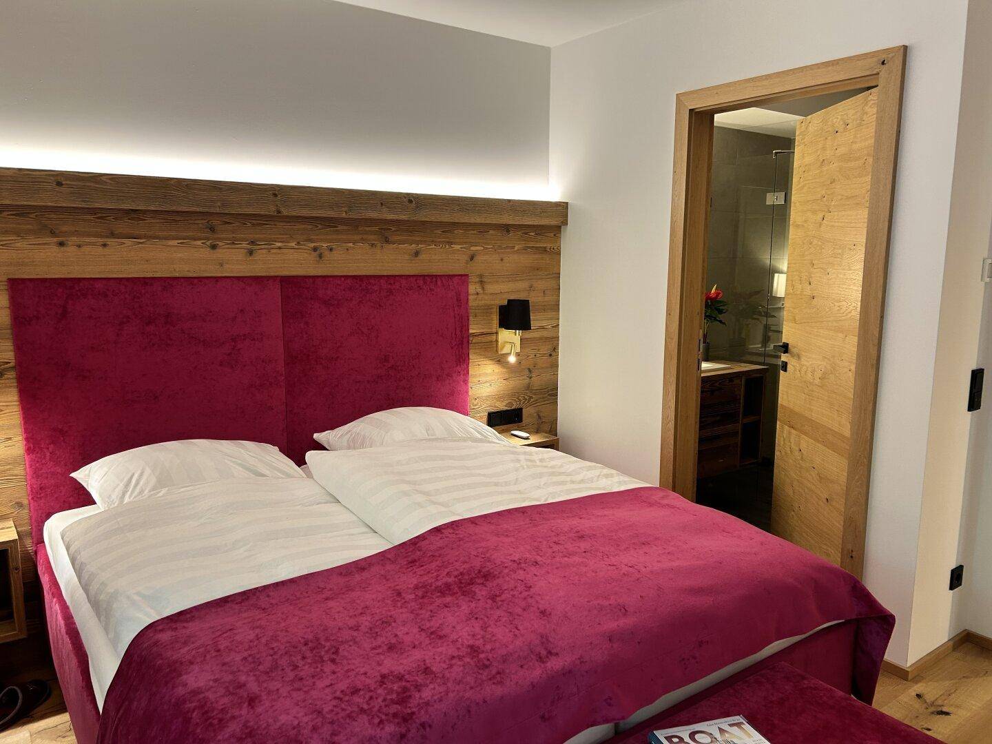 Gemütliches Schlafzimmer mit großem Bett, Holzkopfteil und direktem Zugang zum modernen Badezimmer.