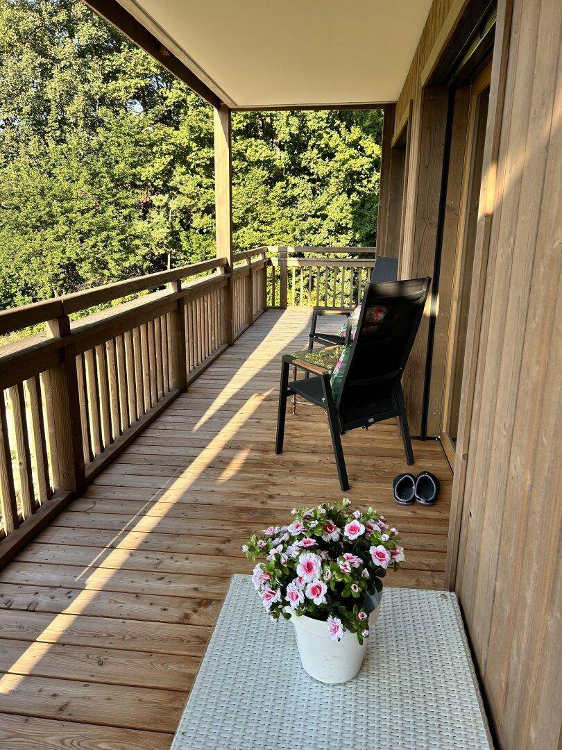 Langer Holzbalkon mit Sitzgelegenheiten und Blick auf die umliegende Natur, ideal zum Entspannen.