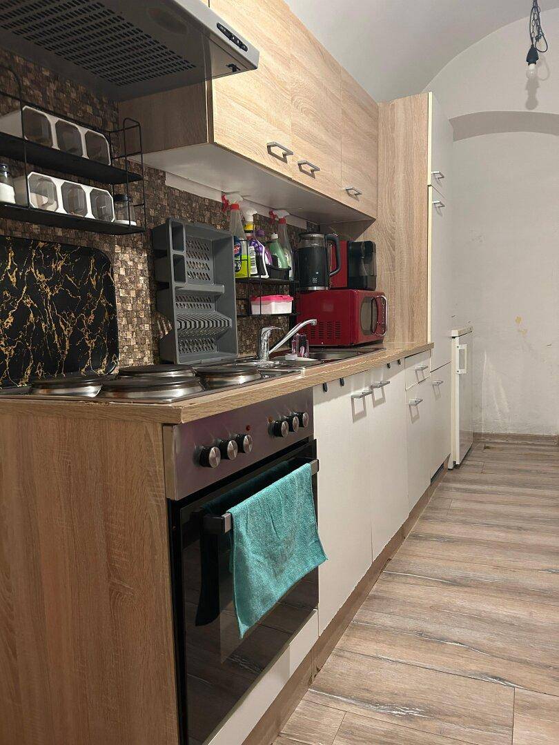 Kleine, funktionale Küche mit Holz- und weißen Schränken, ausgestattet mit Elektroherd und Mikrowelle.
