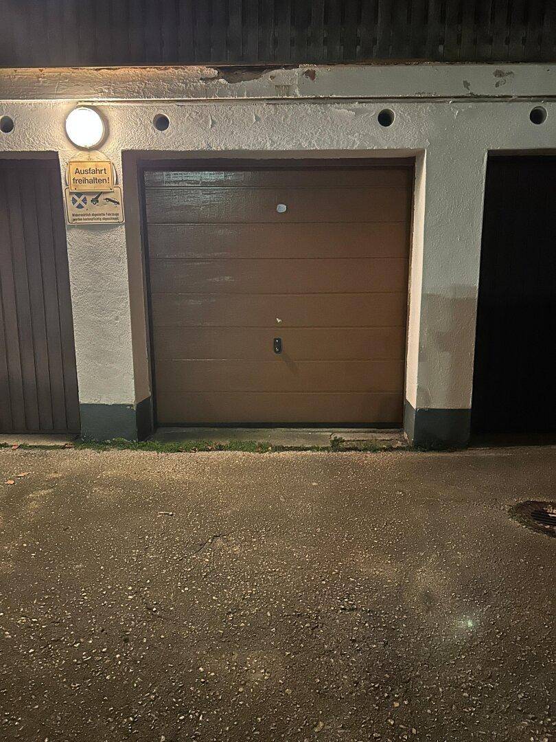 Garagentor bei Nacht, Teil einer Reihe von Garagen mit einfacher Beleuchtung.
