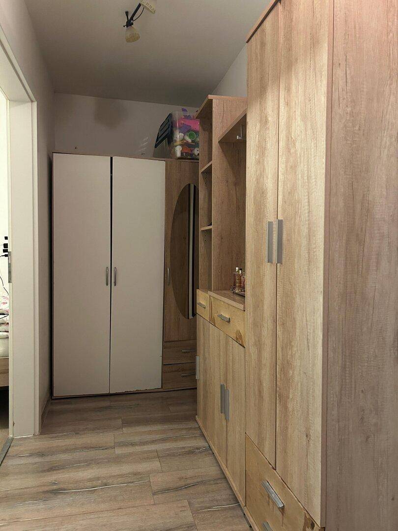 Flur mit Holzschränken und Laminatboden, bietet Stauraum und einen Spiegel.