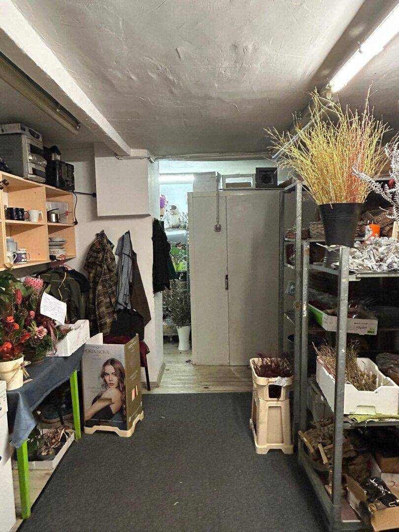 Hinterer Bereich des Blumenladens, genutzt als Lager- und Arbeitsfläche mit Regalen und Arbeitsutensilien.