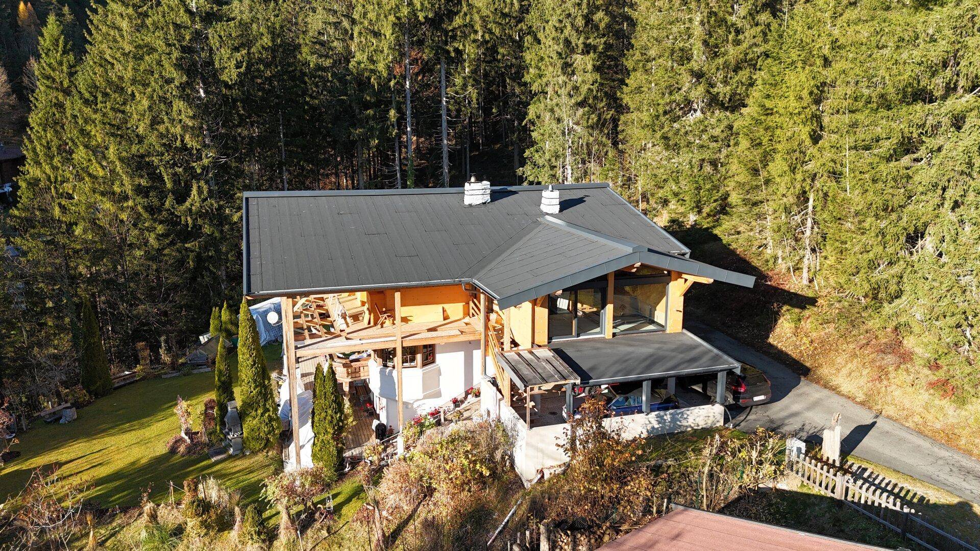 Luftaufnahme eines im Bau befindlichen Chalets, das sich harmonisch in die bewaldete Umgebung einfügt.