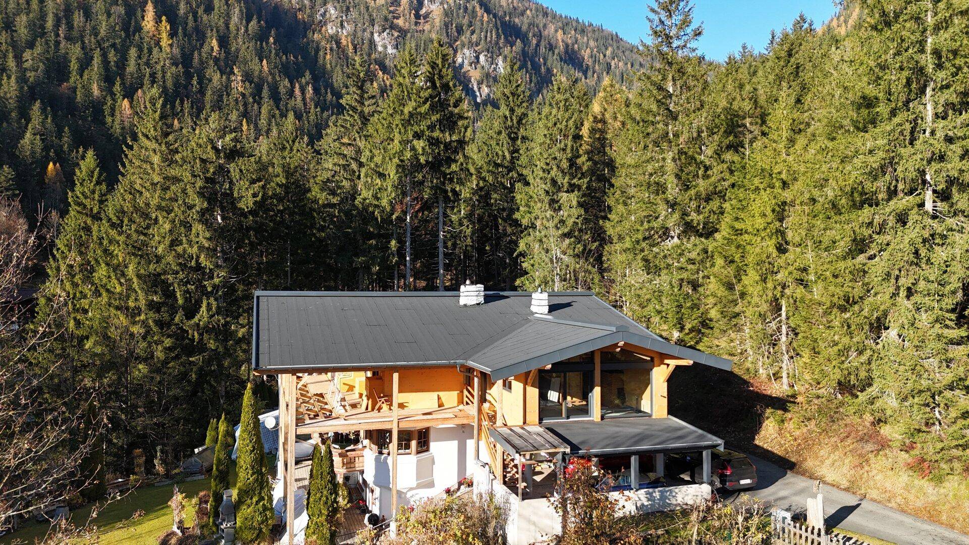 Luftaufnahme des fast fertiggestellten Chalets, eingebettet in die grüne Waldlandschaft.
