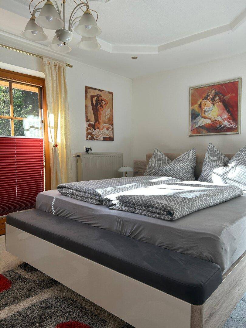 Helles Schlafzimmer mit Doppelbett, Zugang zu einem Balkon und viel natürlichem Licht.