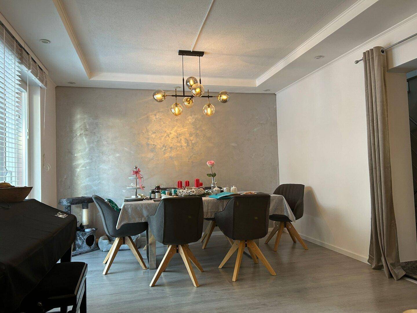 Eleganter Essbereich mit modernem Kronleuchter, stilvoller Wandgestaltung und hellem Laminatboden.