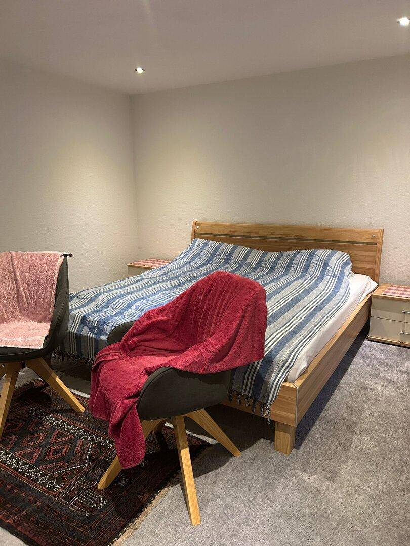 Schlafzimmer mit Doppelbett, Teppichboden und indirekter Deckenbeleuchtung für eine gemütliche Atmosphäre.