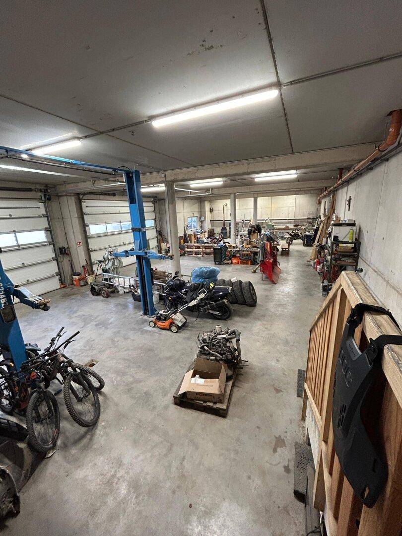 Große Werkstatt mit Hebebühne, Werkzeugen und verschiedenen Fahrzeugen.