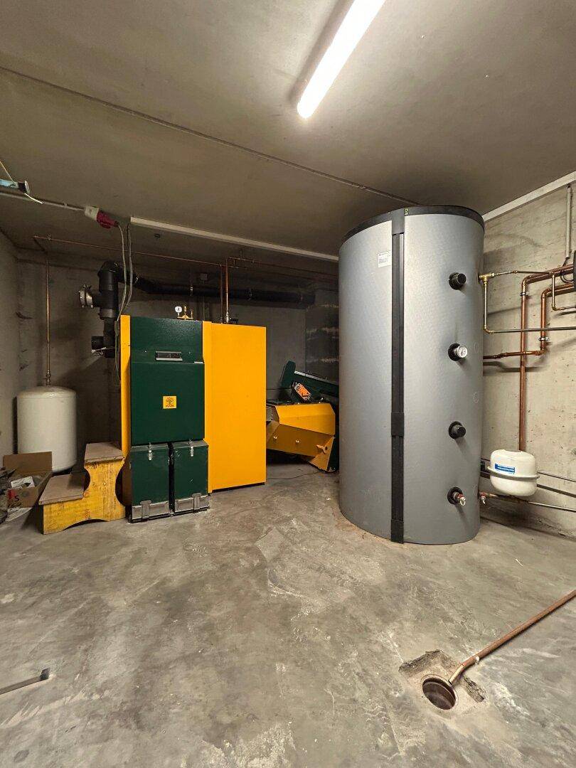 Heizungsraum im Keller mit großem Warmwasserspeicher und Heizkessel.