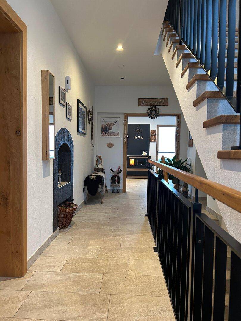 Heller Flur mit Fliesenboden, Holztreppe und traditionellen Dekorationselementen.