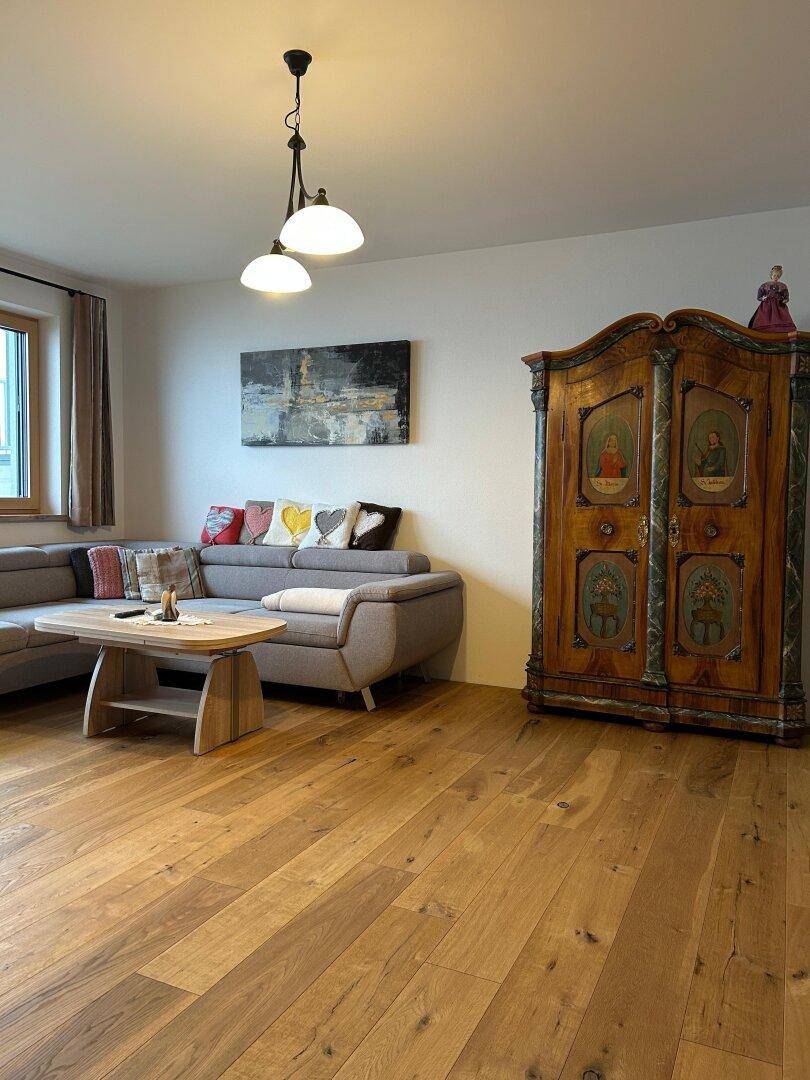 Gemütliches Wohnzimmer mit Holzboden, bequemer Couch und antikem Schrank.